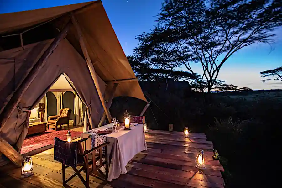 Interno di un luxury tented camp con letto a baldacchino e vista sulla riserva naturale