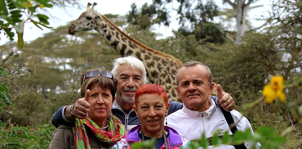 Turisti in cammino tra zebre e giraffe al Lago Naivasha durante l'Expedition Kenya Safari